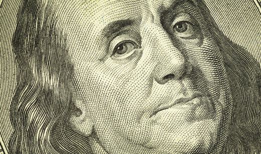 A close up view of Benjamin Franklin on a one humdred dollar bill.
