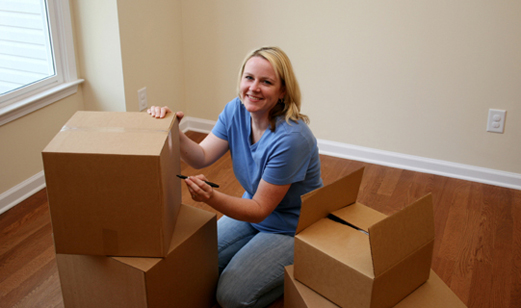 A woman packing up her things, and using a marker to describe what is in each box she had packed.