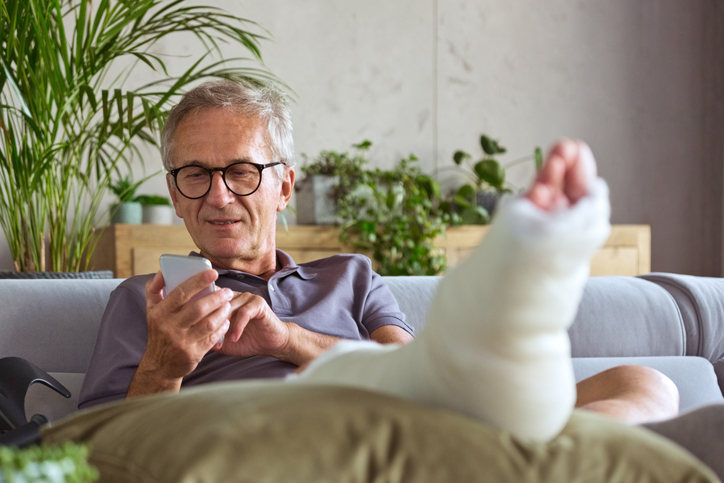 Man with a foot cast, looking at his phone