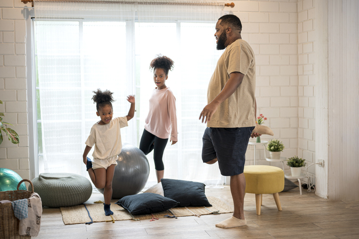 Father exercising at home with his two young daughters