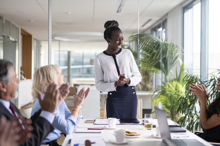 A group applauding a woman in a meeting.