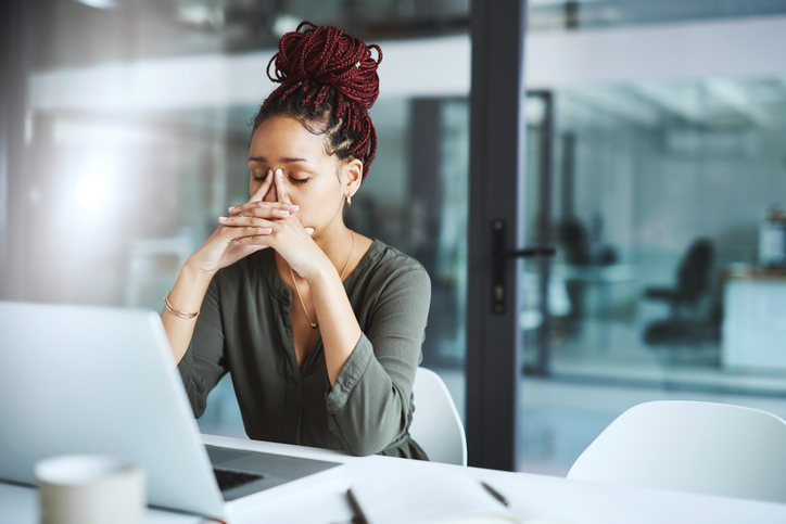 Frustrated, stressed woman in front of laptop in an office.