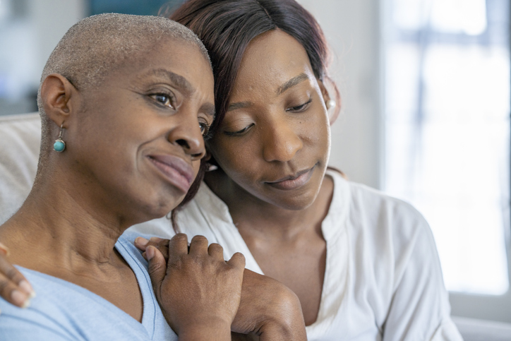 Younger woman with her arm around an older woman.