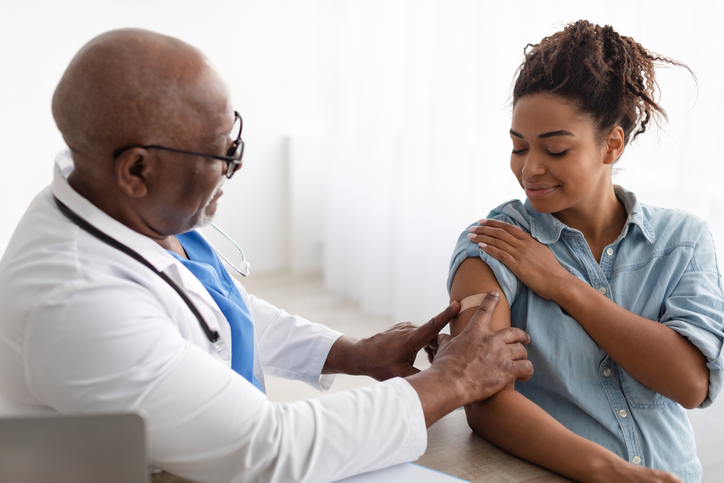 Doctor applying bandaid to woman's arm.