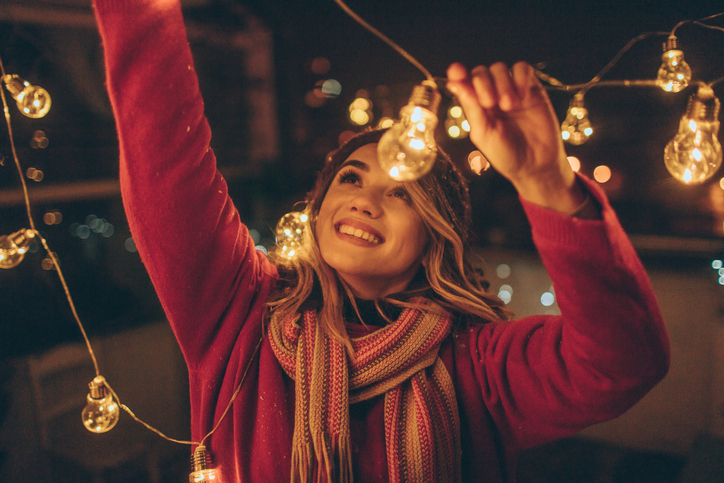 Woman hanging lights on balcony deck