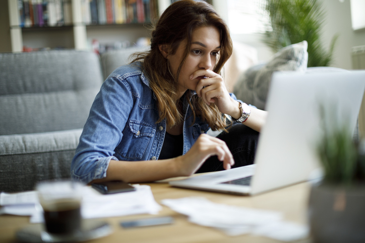 Worried young woman working on a laptop.
