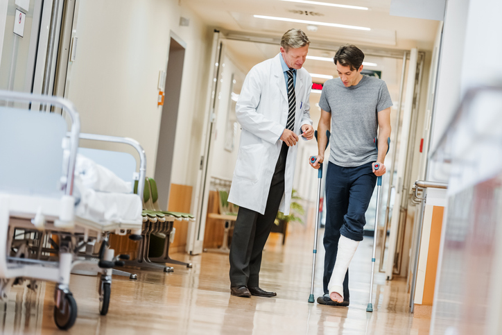 Man with a cast on his leg talking with a doctor.