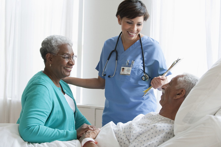 Nurse speaking to older couple in hospital.