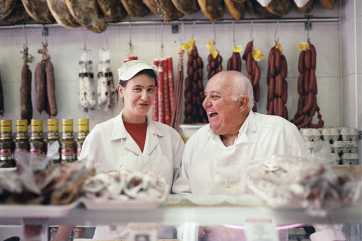 Two people standing behind a butcher counter.