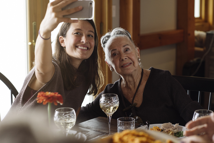 Two family members taking picture at dinner table.
