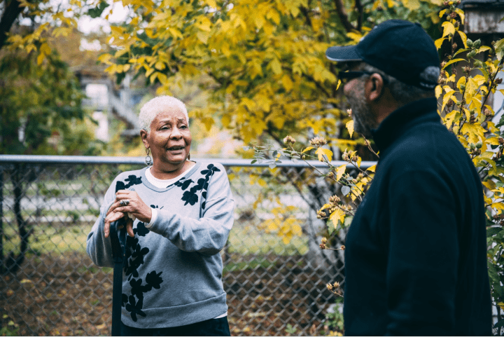 Man and woman talking in yard.