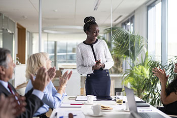 A group applauding a woman in a meeting.