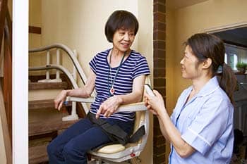 Younger woman helping older woman in a chair lift.