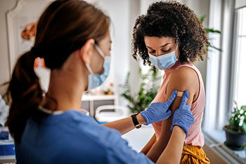 Nurse putting bandaid on woman's arm.