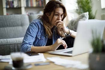 Worried young woman working on a laptop.