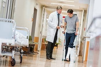 Man with a cast on his leg talking with a doctor.