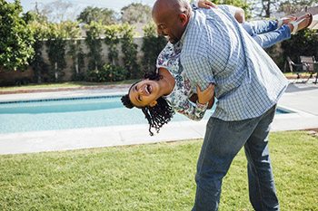 Father and daughter playing and laughing in their backyard.