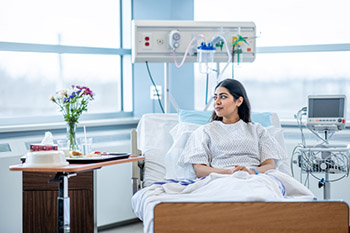 Woman in hospital bed looking out of a window