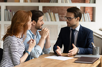 Man in suit speaking to couple.