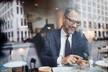 Man looking at phone and smiling in a coffee shop.