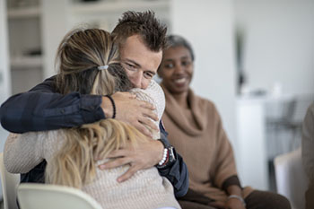 Two people hugging in a support group