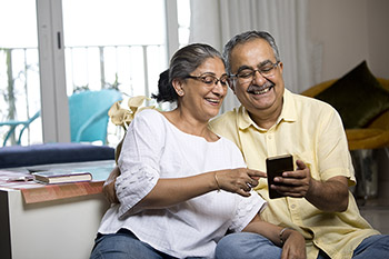 Older couple looking at cellphone together and smiling.