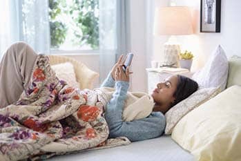 Woman looking at phone in bed.
