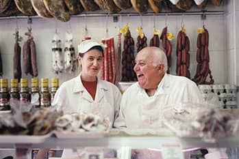 Two people standing behind a butcher counter.