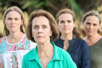 An older woman and her three daughters standing in the background.