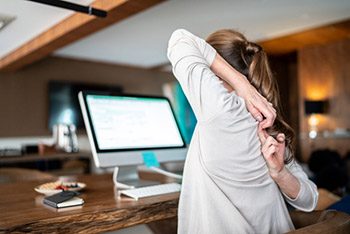 Woman stretching at her computer desk.