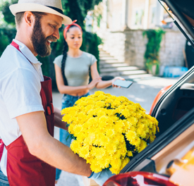 Man putting flowers into the back of a car./ 