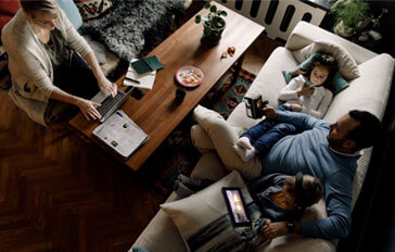 Family relaxes in living room while looking at their phones and computers.