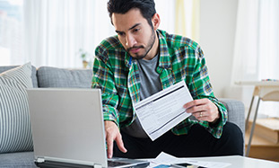 man sitting on sofa doing bills. 