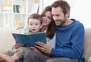 A father and son sit together at a table smiling. 