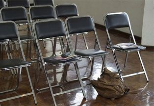 Backpack left under row of folding chairs. 