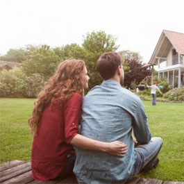 Couple watches their child play in the yard. 