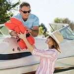 A man and woman get ready to take their boat out on a sunny day. 