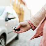 A woman is holding her car key and walking towards her car. 