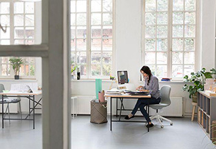 Woman sitting in loft office looking at paperwork.