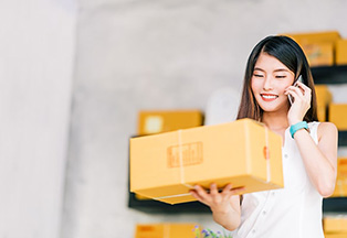 Woman talking on the phone while holding on to a package.