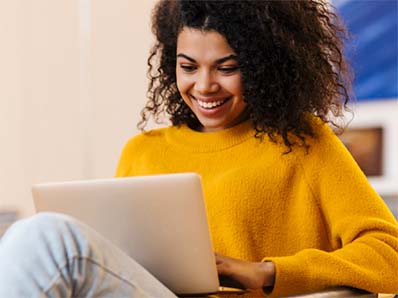Young woman smiling while using her laptop. 