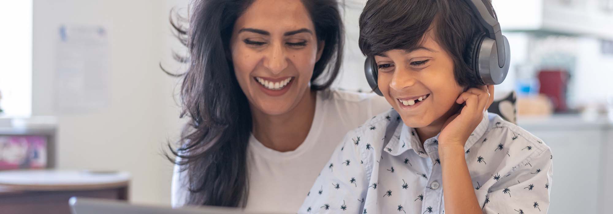 A young couple sitting on the floor in the living room looking at laptop.  