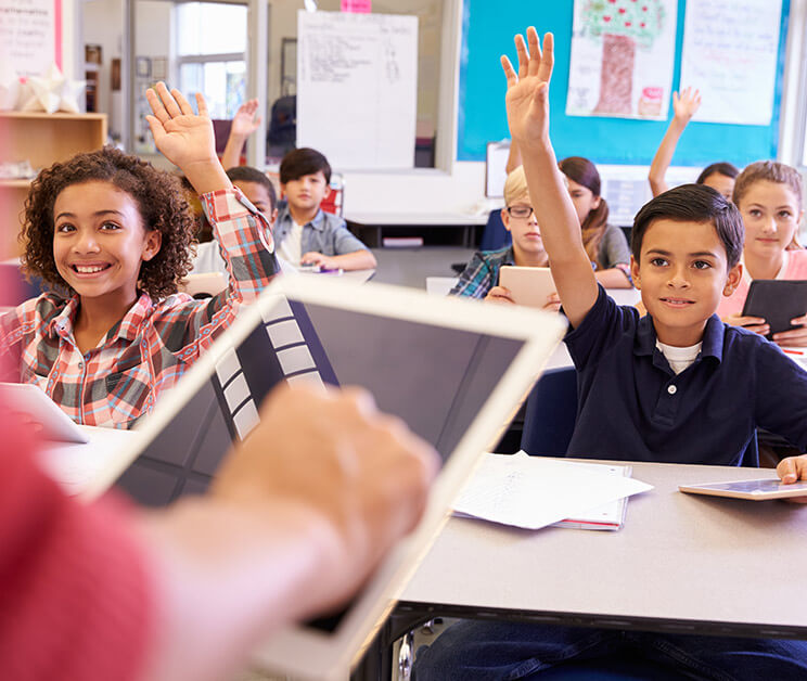 Students raising their hands to answer a question. 