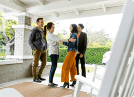 Two couples talk on the front porch of a modern home.