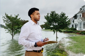 Man with clip board looking at damage of home. 