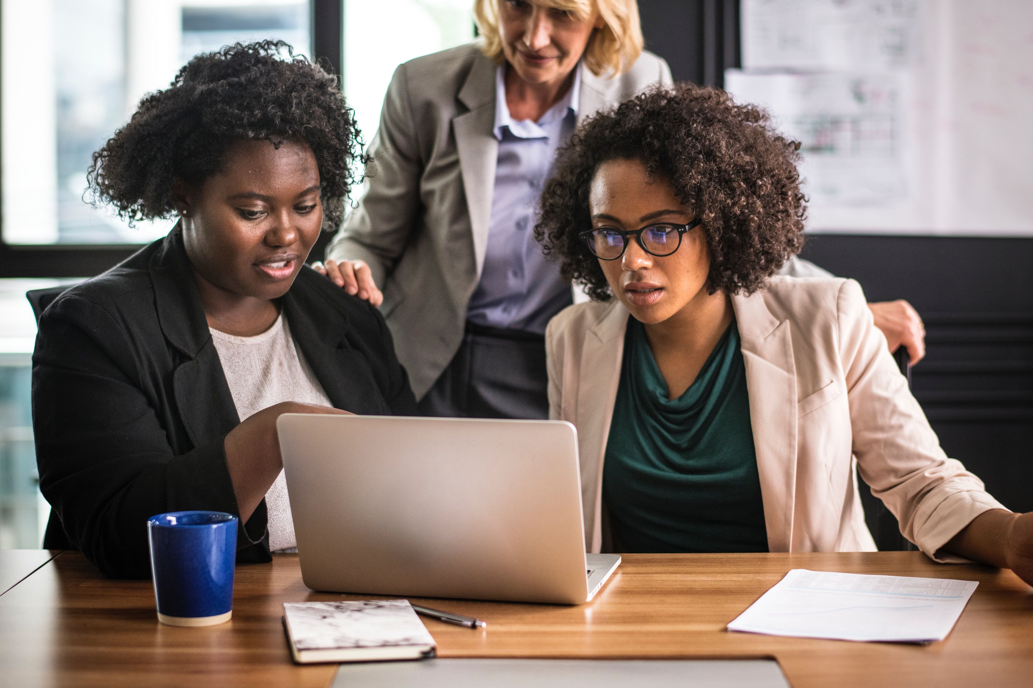 Two woman looking over a laptop. 