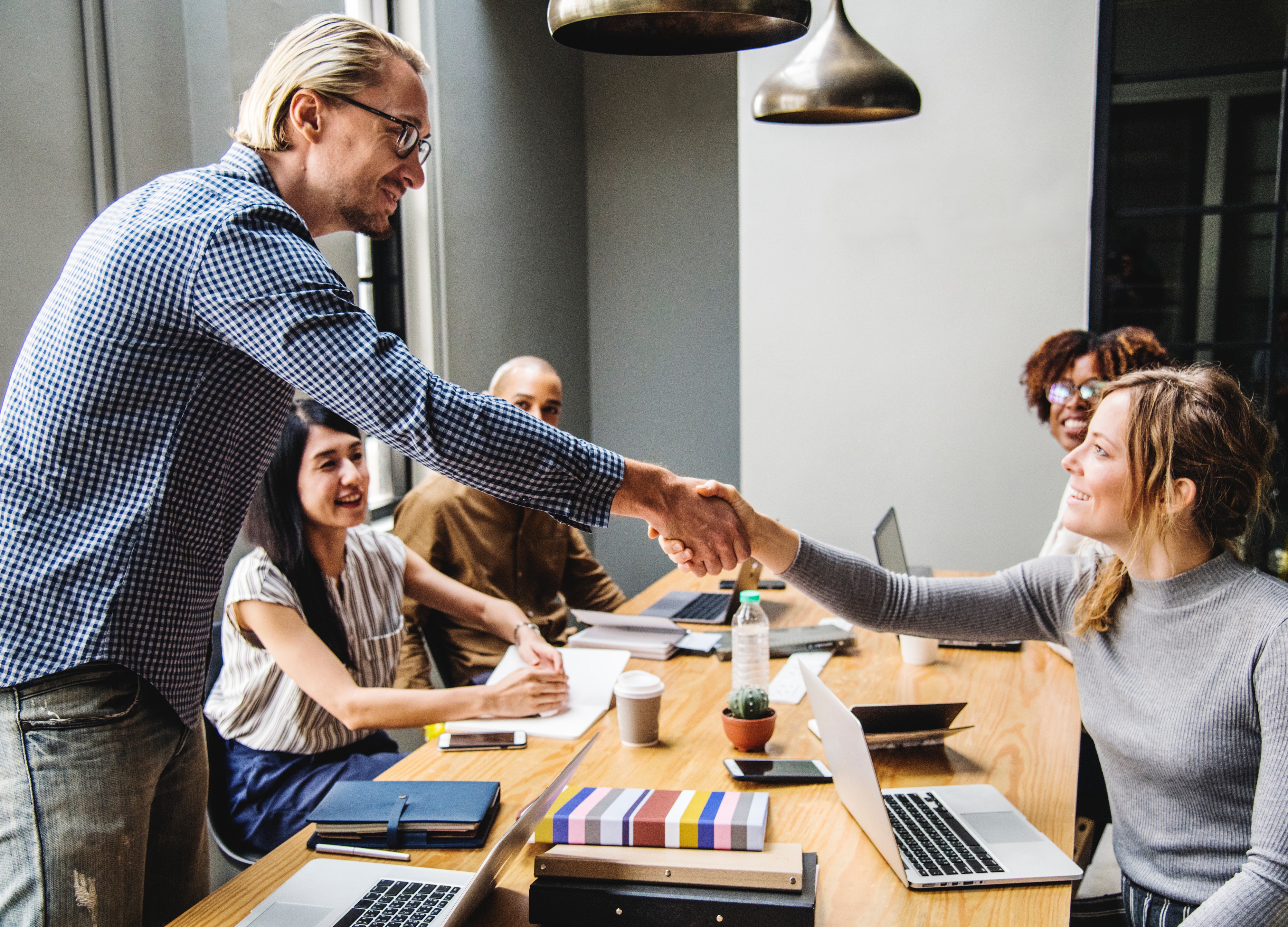 Manager shaking an employee's hand in a meeting.