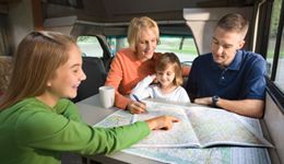 A family looking at an atlas in their motorhome planning their trip. 