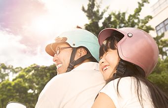A couple enjoying riding a scooter.