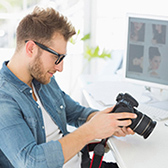 Male photographer looking at camera in from of computer. 